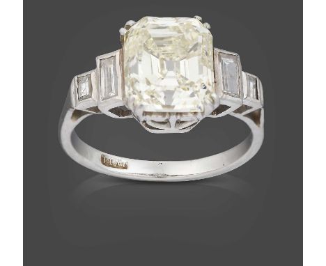 the central emerald-cut diamond in a white double claw setting, flanked by pairs of graduated baguette cut diamonds in rubbed