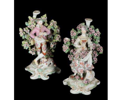 A PAIR OF 18TH CENTURY DUESBURY &amp; CO DERBY PORCELAIN CANDLESTICKS - MUSICAL SHEPHERD &amp; SHEPHERDESS patch marked bases
