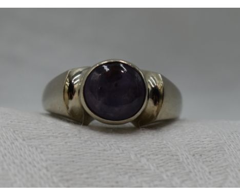 A lady's dress ring of Artisan form having a star sapphire cabochon in a collared mount to shaped shoulders on a 9ct white go