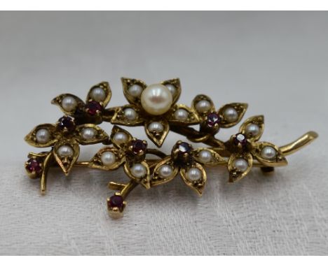 A 9ct gold brooch modelled as a bunch of flowers having cultured and seed pearl and ruby decoration