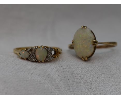 A lady's dress ring having three opals (1 missing) interspersed by diamond chips in a gallery mount on a yellow metal loop st