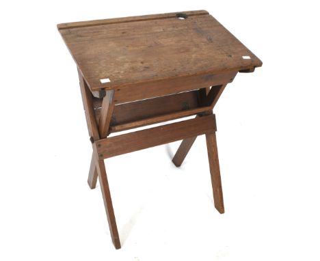 A vintage stained pine folding 'school' desk. The sloped top fitted with an inkwell, L61cm x D42cm x H76cm