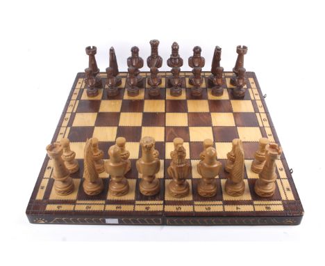 A large carved wooden chess set and matching folding board. Complete, King H14cm, board when open 59cm x 59cm