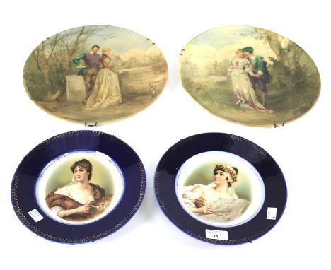 A pair of painted glass chargers and two French porcelain portrait plates. Circa 1900, the first painted with couples in hist