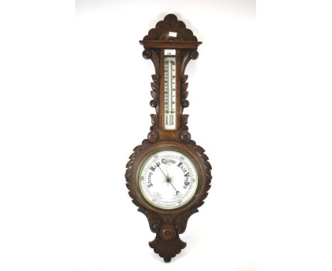 An oak aneroid wall barometer with Fahrenheit and centigrade thermometer. With allover carved decoration, L89cm