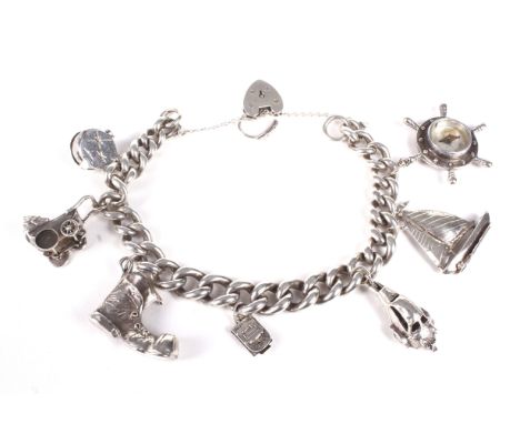 A white metal curb link charm bracelet and charms. On a padlock clasp stamped 'Silver'. Hung with seven various charms includ