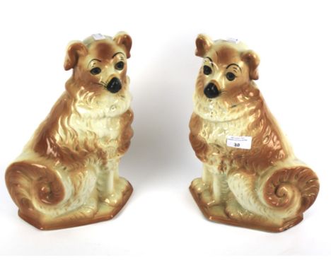 A pair of Staffordshire pottery 19th century style models of dogs. Each modelled seated on its haunches, enriched in light br