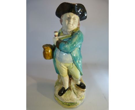 Early 19th Century Wood Type Pearlware Toby Jug of a standing man holding a pipe across is chest and to the other hand a brow