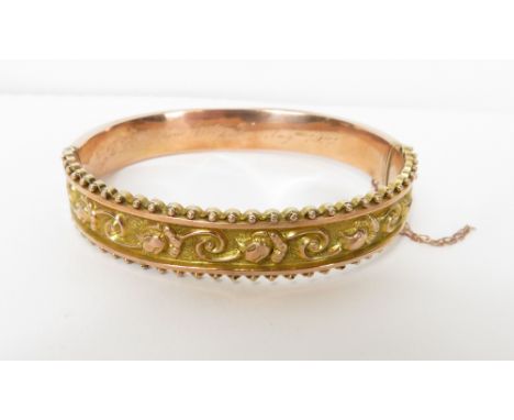 A 9 carat gold hinged bangle, Birmingham 1910, embossed with flowers to both halves, beaded border to the frontispiece, 1.2 c