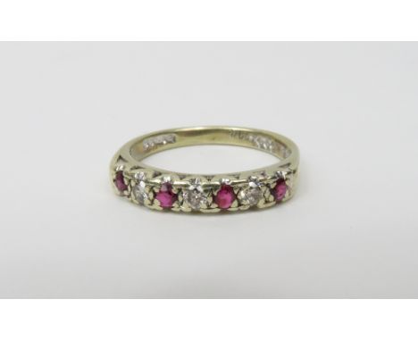 A 9 carat white gold ruby and diamond half hoop ring, set with four rubies and three diamonds, the brilliant cuts totalling a