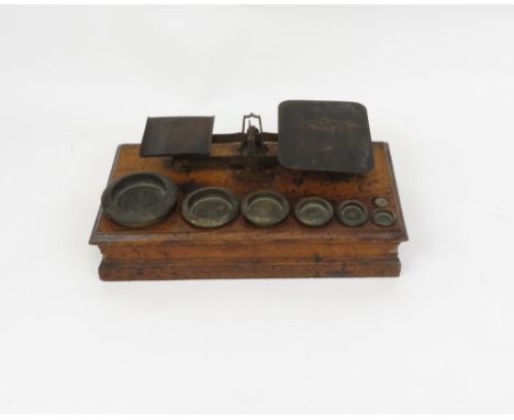 A 20th century set of weighing scales, with seven brass weights on an oak base