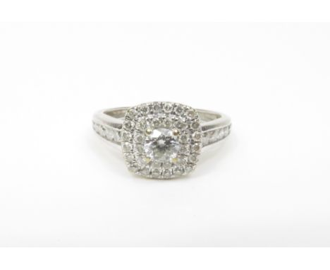 A diamond cluster ring, the white mount stamped '18K', with a central brilliant cut, enclosed by a cushion shaped head set wi