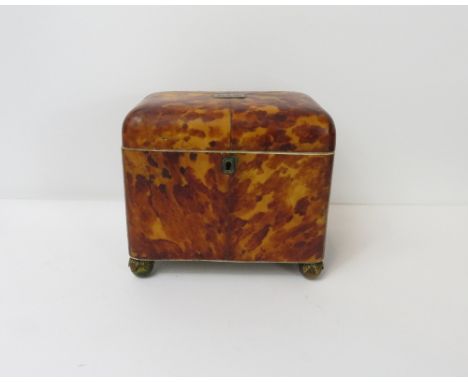 A 19th century tortoiseshell tea caddy, the interior with two wooden faux tortoiseshell lids with an ivory border on four bra