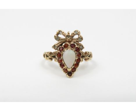 A 9 carat gold opal, garnet and diamond cluster ring, the opal enclosed by thirteen garnets, with a ribbon bow surmount set w