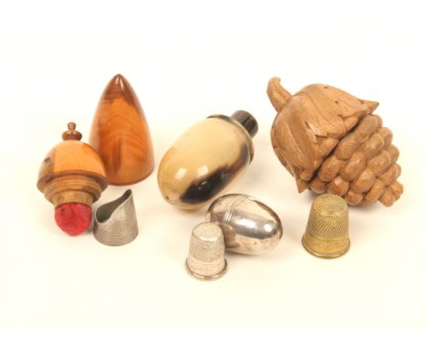 Four thimble cases, comprising; a turned yew wood example fitted with a pin poppet and with a silver finger guard, 6.5cm, a c