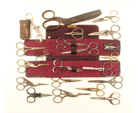 A collection of scissors, including three stork form pairs, two folding pairs, button holing pair, and a leather case contain