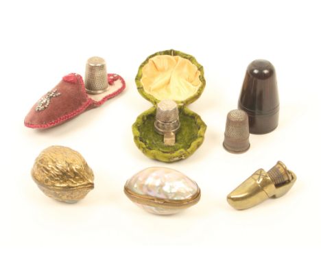 Six thimble cases, comprising; a mother-of-pearl egg, 4cm, a cast metal walnut, a brass shoe with thimble, a velvet slipper w