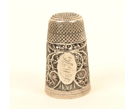 A late 18th century English silver filigree thimble, formerly with scent bottle base, deep quill work border with an oval car