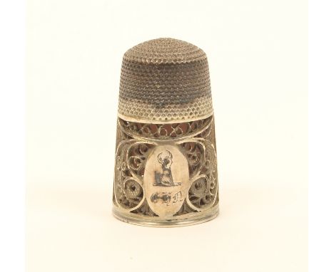 An early 19th century English silver filigree thimble, the quill work border with an oval cartouche, engraved with a fist hol