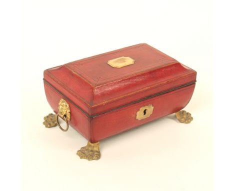 A Regency red leather covered sewing box for a child, of sarcophagus form, on gilt lion paw feet with gilt lion mask ring sid