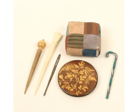 A mixed lot, comprising; a sepia fern ware pin disc, 4.7cm, a silk patchwork pincushion, an engraved silver bodkin, a turned 