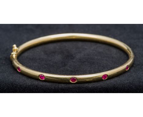 A Thurlow and Champness ruby set 18 ct gold braceletOf hinged bangle form, boxed.  6.5 cm wide. 