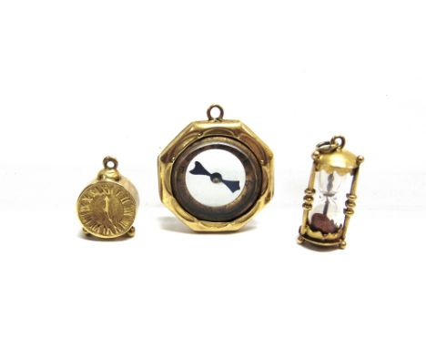 A GROUP OF THREE EARLY 20TH CENTURY GOLD CHARMS OR PENDANTS  comprising; a gold mounted compass of octagonal outline, stamped