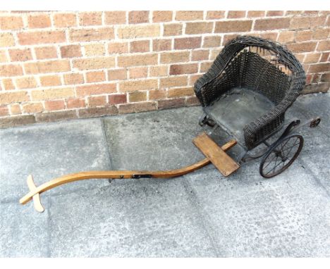 A LATE VICTORIAN CHILD'S PULL-ALONG CHAIR  with a woven wicker seat surround and shallow, rexine-covered padded seat, a foldi