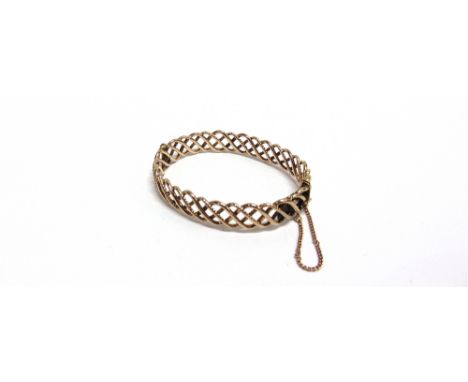 AN EARLY 20TH CENTURY ROSE GOLD HOLLOW HINGED BANGLE of hollow entwined polished and rope-twist design, on a push-snap stampe