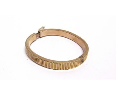 AN EARLY 20TH CENTURY ROSE GOLD HOLLOW HINGED BANGLE of hollow reeded-rectangular section, on a push-snap stamped '9ct', appr