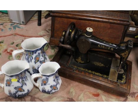AN OAK CASED VINTAGE SINGER SEWING MACHINE TOGETHER WITH A SET OF THREE GRADUATED LOSOL WARE BUTTERFLY PATTERN JUGS (4) 