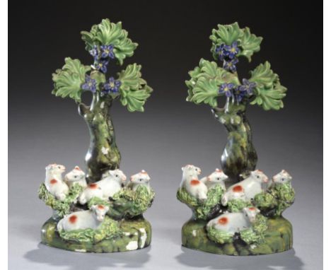 A PAIR OF STAFFORDSHIRE PEARL GLAZED EARTHENWARE GROUPS OF LAMBS BENEATH A TREE, C1815-25  with enamel painted decoration, 17