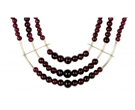 A SOUTH EAST ASIAN THREE STRAND NECKLACE OF GARNET BEADS, C MID 20TH C with white metal spacers, beads 0.4-0.8cm  Provenance: