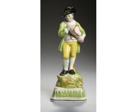 A STAFFORDSHIRE PEARLWARE FIGURE OF FLEMISH MUSIC, C1800 in the form of a man playing the hurdy gurdy, 23cm h   The same mode