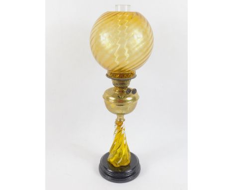 A brass oil lamp, raised on a Murano glass fluted base, black circular socle, with glass chimney and spiral fluted yellow gla