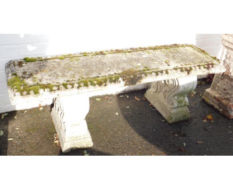 A concrete garden bench, the rectangular top raised on two scroll supports, 44cm H, 127cm L, 38cm D. 