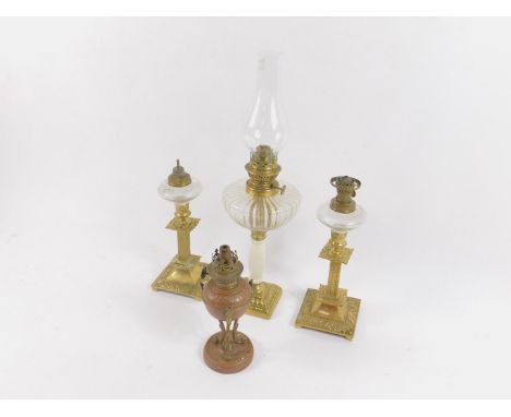 A pair of brass oil lamps of squat candlestick form, a hammered copper oil lamp, and a brass and ceramic oil lamp, clear glas