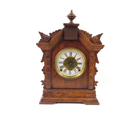 An American late 19thC oak cased mantel clock, brass circular dial with white enamel chapter ring bearing Roman numerals, eig