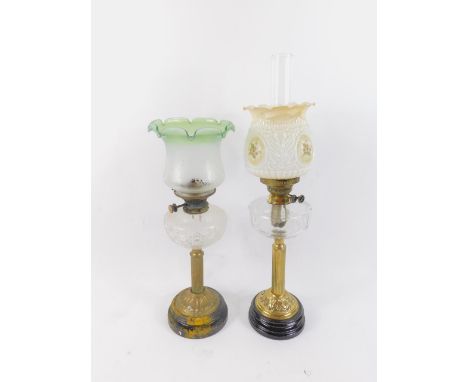 A duplex brass oil lamp, raised on a black pottery socle, with faceted clear glass reservoir and opaline glass shade with res