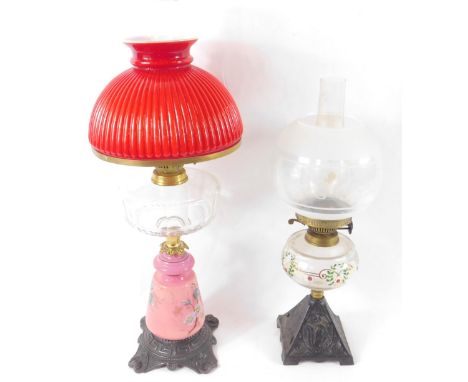 A Continental late 19thC pink glass and cast iron oil lamp, painted with flowers, with a faceted clear glass reservoir, chimn