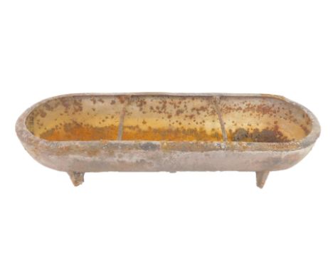 An oval cast iron pig's trough, raised on four feet, 76cm long.