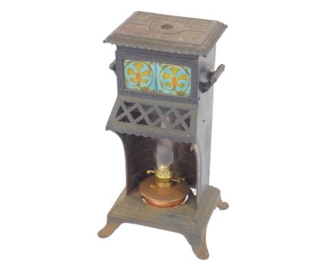 A Victorian cast iron Cathedral heater, inset with two floral tiles, containing a copper oil lamp, raised on outswept feet, 7