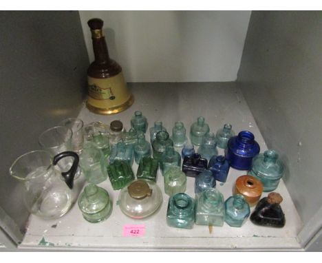 A collection of glass inkwells, a ceramic inkwell, a glass jug, and a Wade Bells Scotch Whisky bottle 