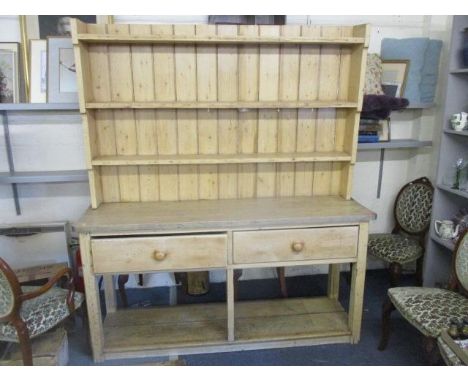 A large Victorian pine dresser having a plate rack above two short drawers and shelf below, standing on short block feet, 85"