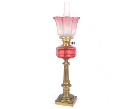 A Victorian brass oil lamp, with flared and decorated cranberry shade and font, height to top of shade 67cmThe shade is chipp