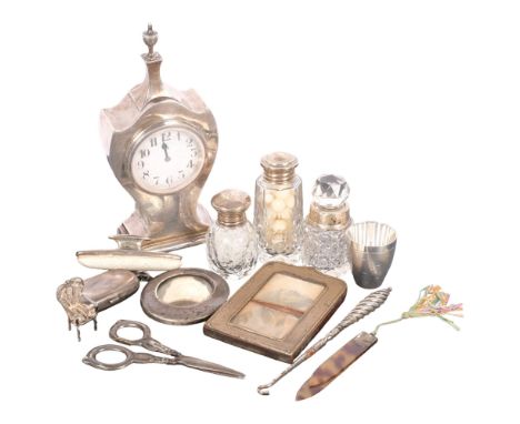 A silver-cased mantel clock, 2 silver-fronted frames, a silver single and double sovereign case, silver-topped scent bottles,