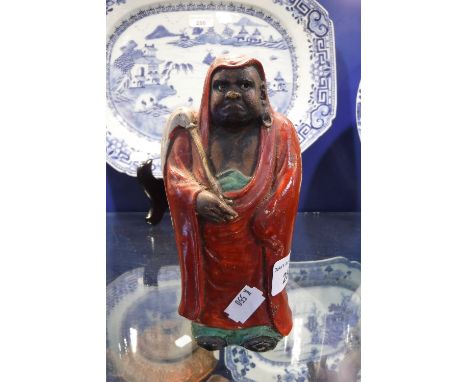 A JAPANESE DECORATED CERAMIC FIGURE OF A MAN in red cloak, 7'' high