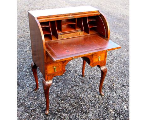 FIGURED WALNUT KNEEHOLE BUREAU WITH A CYLINDER TOP DISCLOSING A FITTED INTERIOR, SLIDE AND FOUR DRAWERS BELOW, ON CARVED CABR