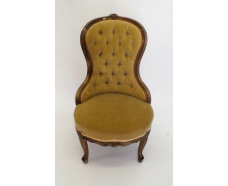 A Victorian yellow button upholstered chair with floral carved decoration 