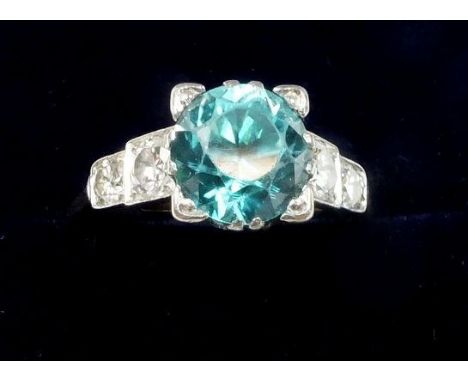 A 1930's Art Deco 18 ct gold and platinum set ring set blue zircon flanked by four diamonds, size O, 4g